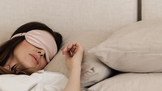 A woman sleeping in her bed with a sleep mask on